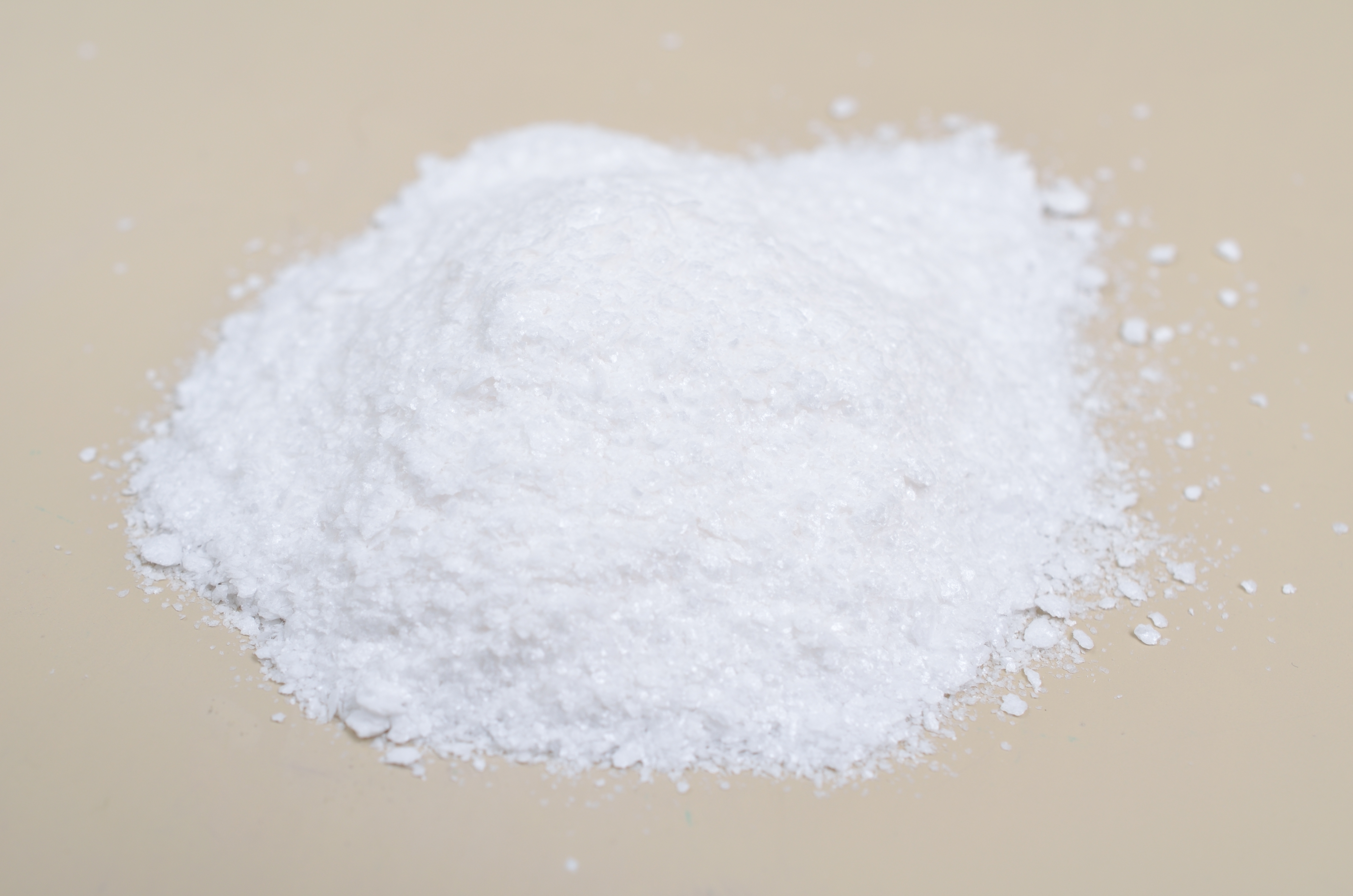 Sodium PCA, ein weißes kristallines Pulver auf beigem Hintergrund, das als hauteigener Inhaltsstoff die Haut mit Feuchtigkeit versorgt.